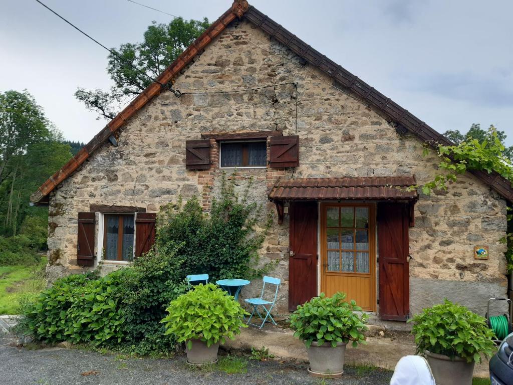 Casa de piedra con 2 sillas y mesa en Gîte * Gaïa *, en Châtel-Montagne