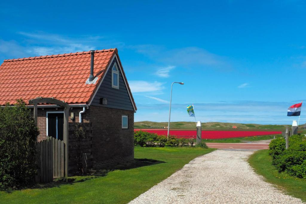 ein Haus mit rotem Dach und roten Blumen in der Unterkunft Vloed in Callantsoog