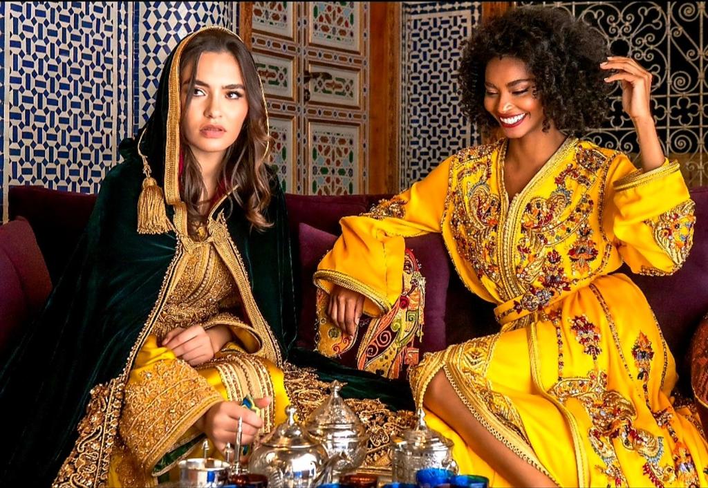 twee vrouwen zitten op een bank bij Riad Fes Nass Zmane in Fès