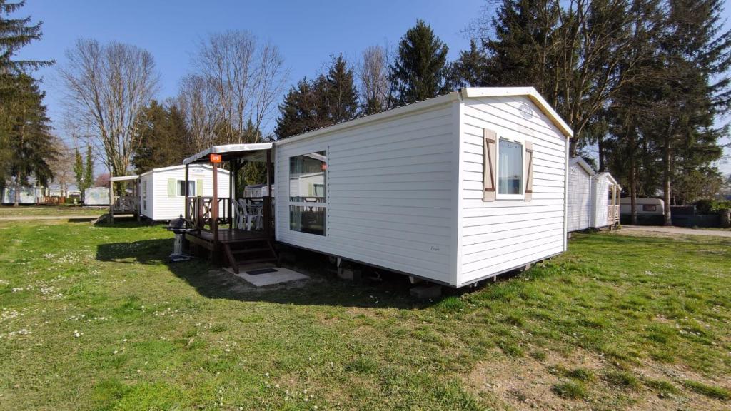 a white tiny house sitting in a yard at Mobil-Home Cosy 5 personnes camping le Ried - Europapark in Boofzheim