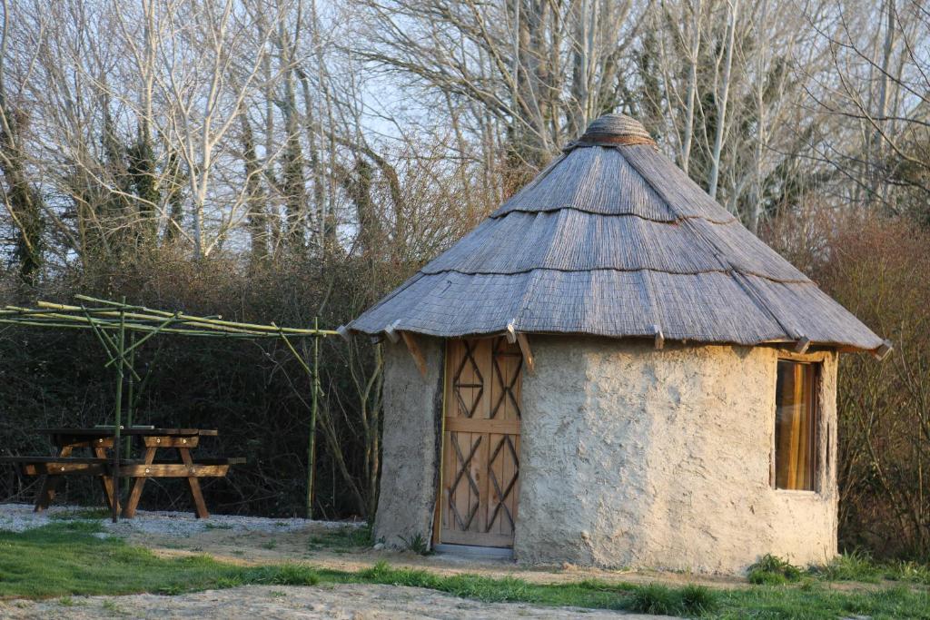 een klein gebouw met een dak met een picknicktafel bij LA HUTTE MASSAÏ in Villelaure