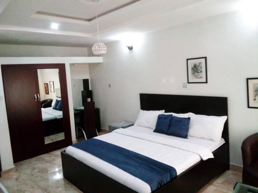 a bedroom with a large bed with blue pillows at PhilBan Suites 1 in Ikeja
