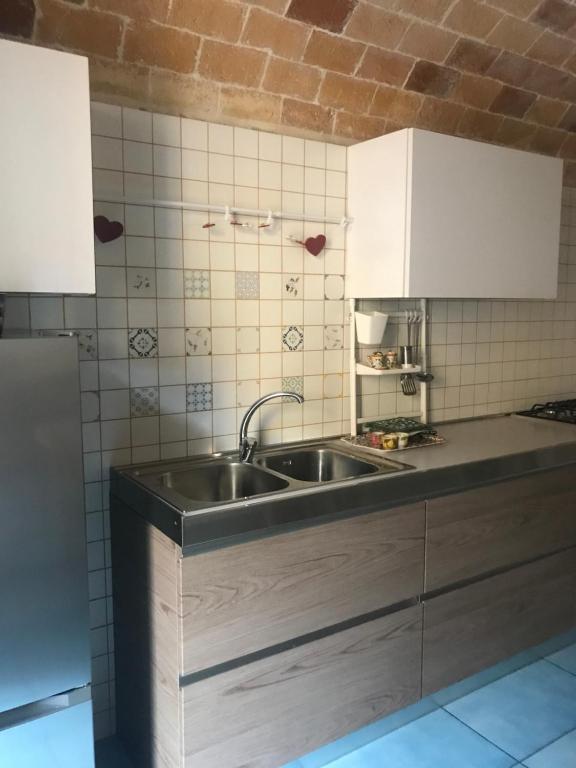 una cocina con fregadero de acero inoxidable y armarios blancos en IL MELOGRANO La Casa nel Vicoletto en Lanciano