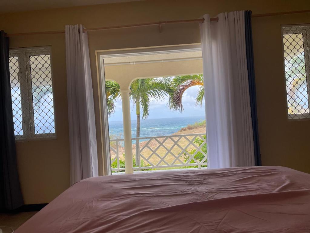 a bedroom with a window with a view of the ocean at ‘MAYARO’ Private Room with Ocean View in Saint Philip