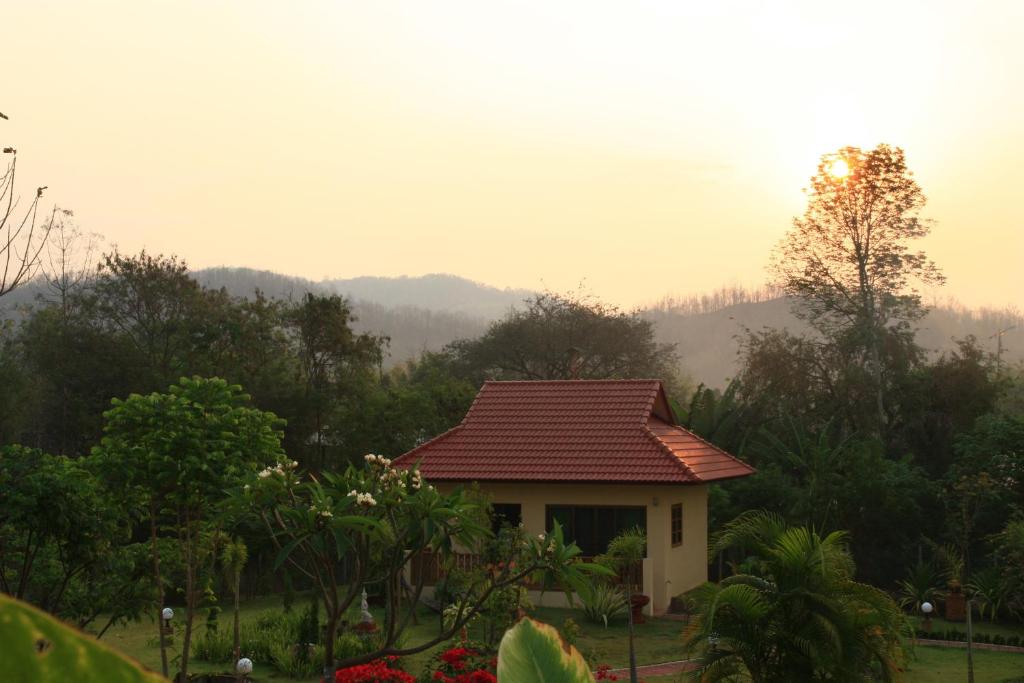 een klein huis met een rood dak in een veld bij Mai Siam Resort in Mae On