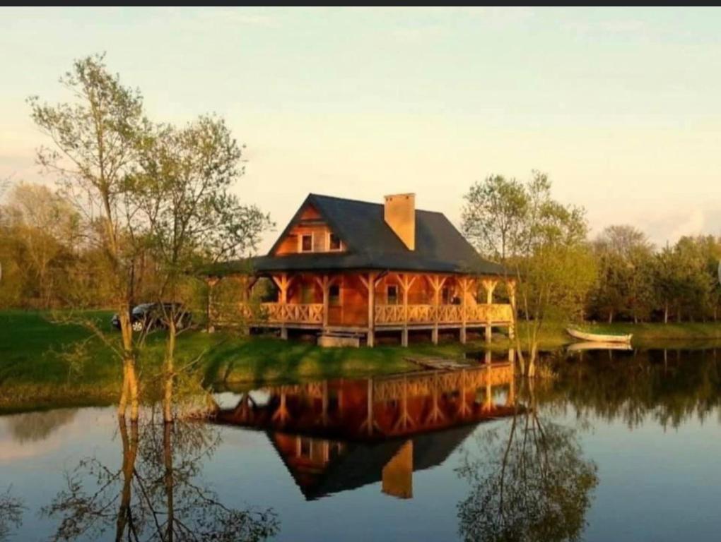 a large wooden house sitting on top of a lake at Przystanek Tonkiele in Tonkiele