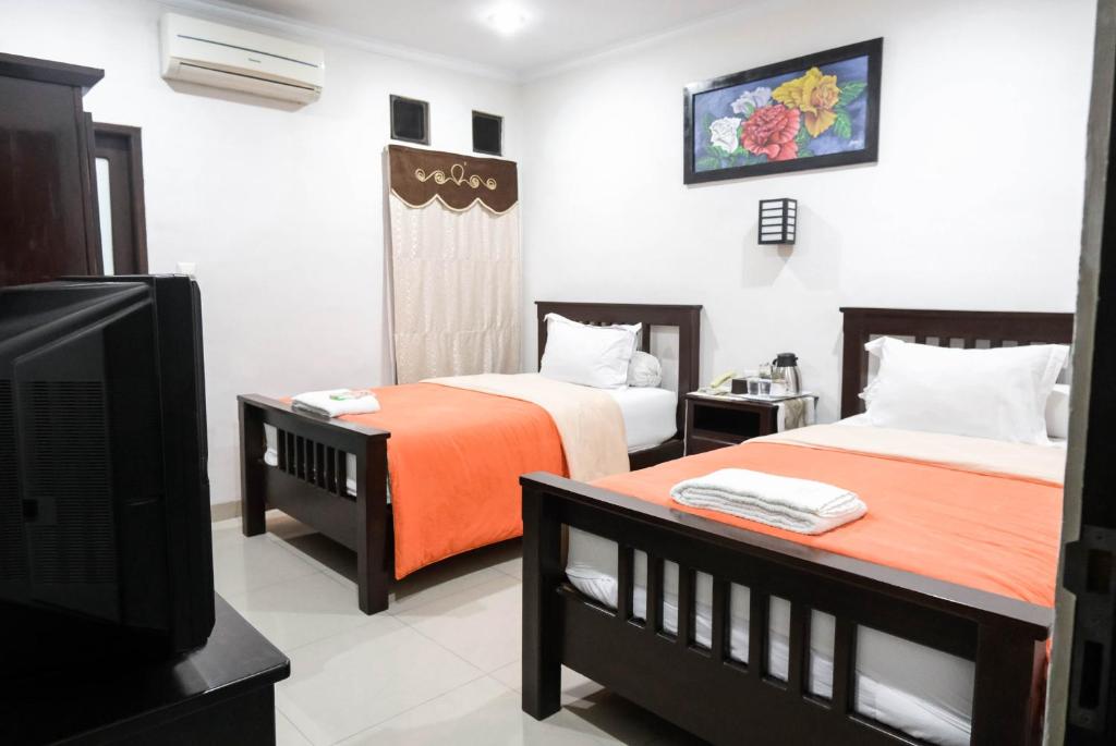 Cette chambre comprend 2 lits et une télévision. dans l'établissement Pasola Guest House, à Medan