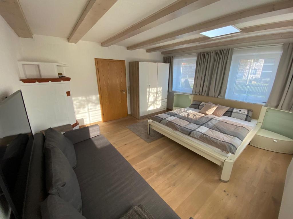 een grote slaapkamer met een bed en een bank bij Gästezimmer Kirchdorf in Unteropfingen