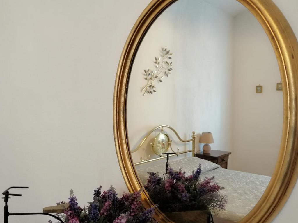 a mirror in a bedroom with a bed and flowers at La Dimora degli Olivi in Torrita di Siena