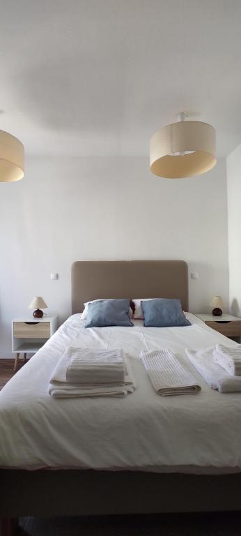 a bedroom with a bed with white sheets and blue pillows at Casa na Costa in Costa Nova
