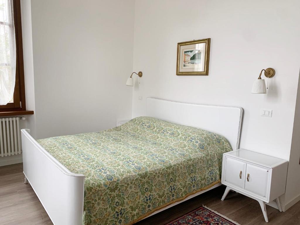 Habitación blanca con cama y mesita de noche en "La Cascina" Bed & Breakfast, en Desenzano del Garda