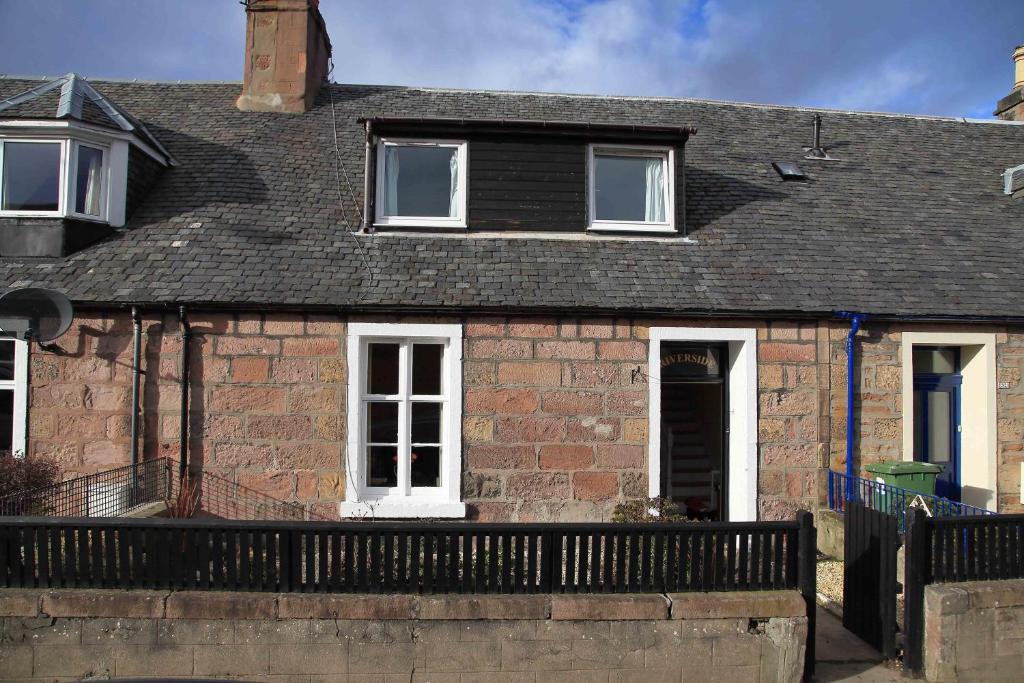 a brick house with a black fence in front of it at Riverside Cottage City Centre in Inverness