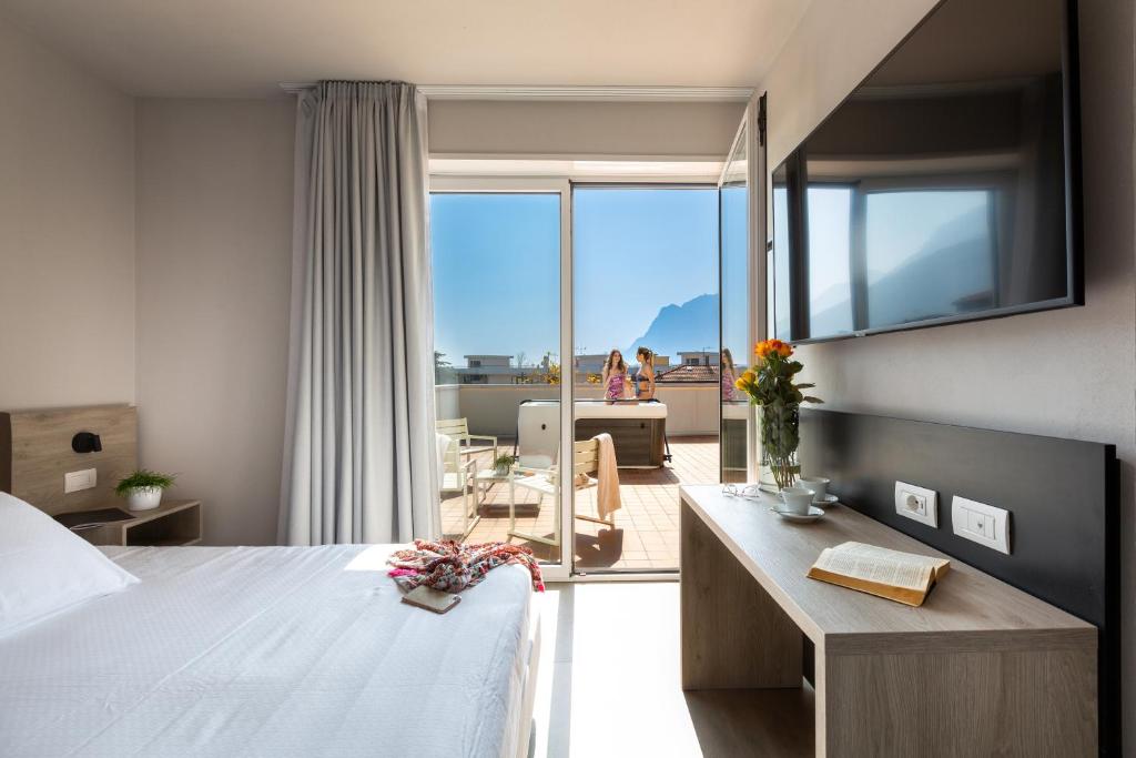 a bedroom with a bed and a view of a balcony at GoTì Hotel in Nago-Torbole