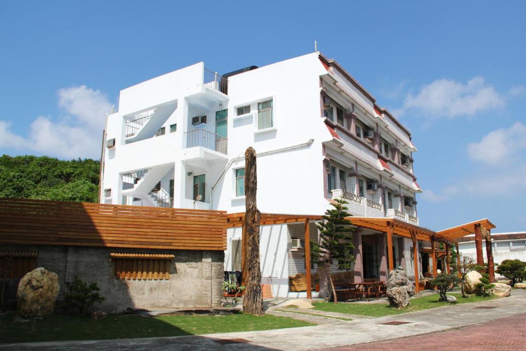a white building with a wooden roof at Star-Moon B&B Green Island in Green Island