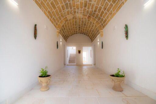 a hallway with a vaulted ceiling and two potted plants at Antiche Dimore in Mazara del Vallo