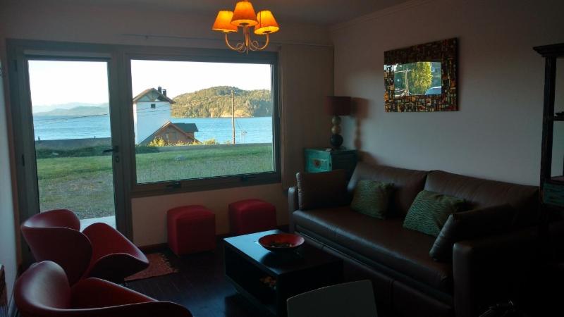 a living room with a couch and a large window at Quintaluna frente al lago in San Carlos de Bariloche