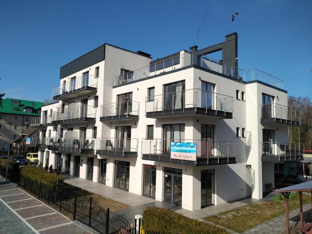 Biały budynek z balkonami na boku w obiekcie Apartamenty HELJAN w mieście Międzywodzie