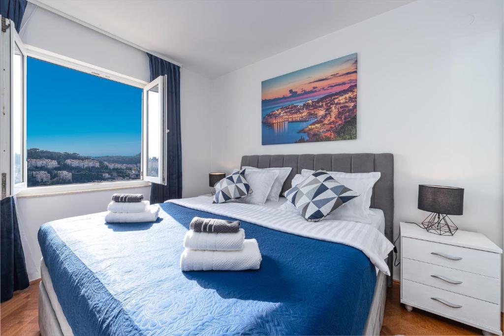 um quarto com uma cama azul e branca e uma grande janela. em BlueSky Deluxe Apartment Free parking em Dubrovnik