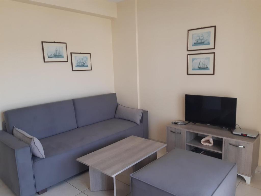 een woonkamer met een blauwe bank en een tv bij Апартамент в Керамоти in Keramotí