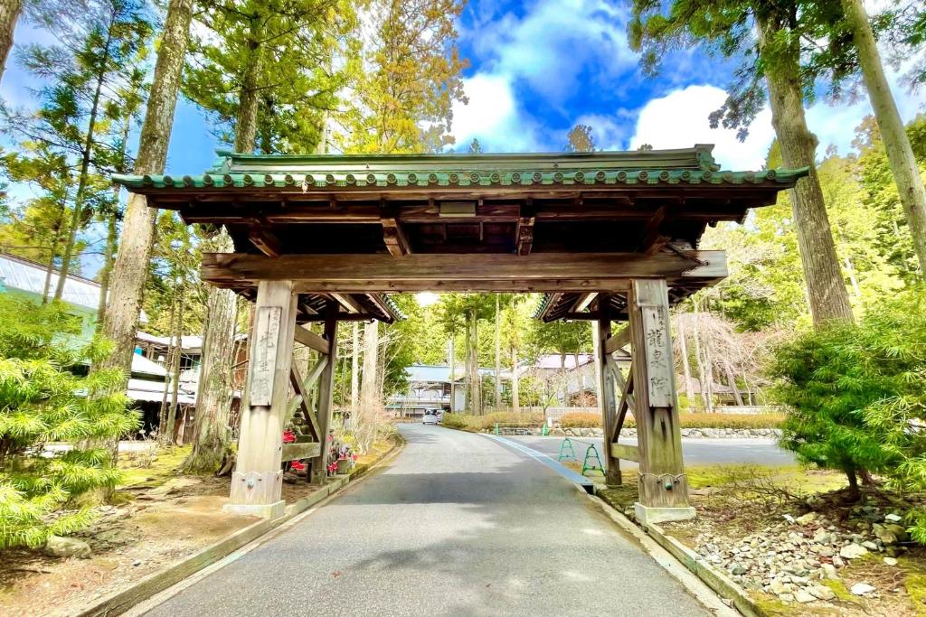 a wooden archway in a park with a road at 高野山 宿坊 龍泉院 -Koyasan Shukubo Ryusenin- in Koyasan