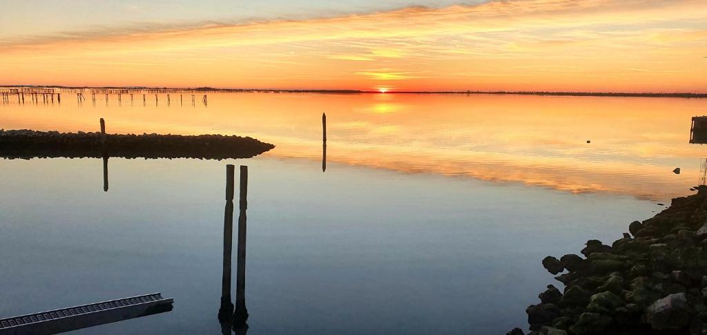 un tramonto su un corpo d'acqua con pali in acqua di Apartments Delise a Scardovari