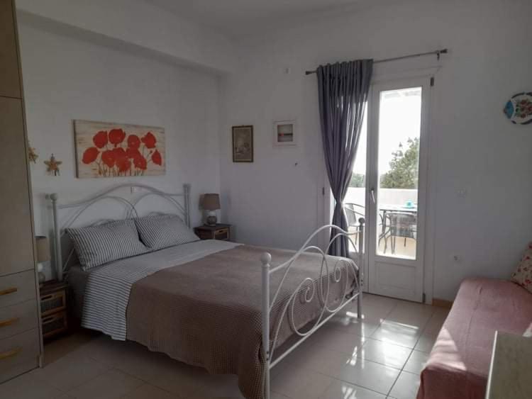 1 dormitorio con 1 cama y puerta corredera de cristal en Glyfada Suite, en Kastraki Naxou