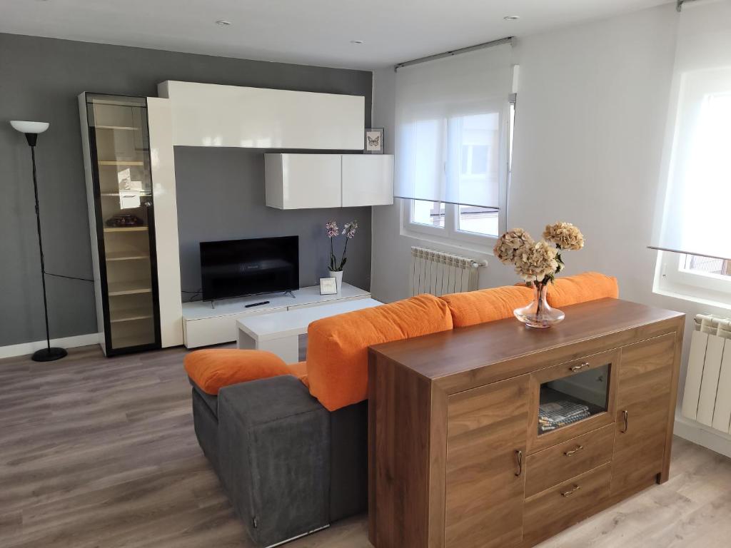 sala de estar con sofá naranja y TV en Apartamento con encanto en Avilés