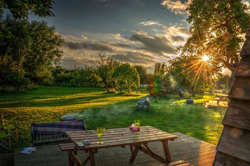 un tavolo da picnic in legno in un giardino con tramonto di Hill Farm and Orchard a Leighton Buzzard