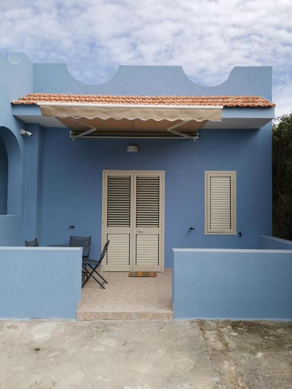 a blue house with a chair in front of it at Casa delle Muse 48 in Fontane Bianche