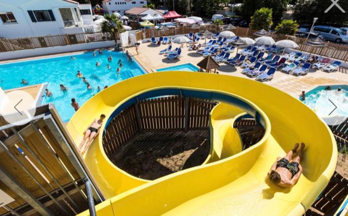 a yellow slide in a pool at a resort at Mobilhome 4/6 pers à 600m de la plage des Conches in Longeville-sur-Mer