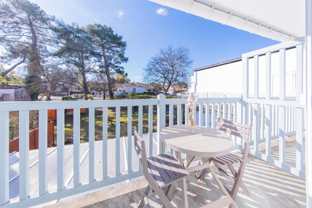 a patio with a table and chairs on a white fence at Hôtel Land'Azur in Mimizan-Plage