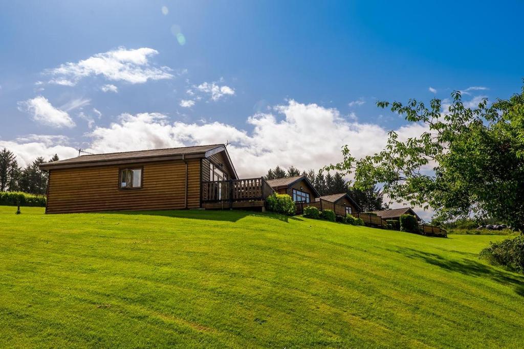 a home on a large grassy field with a house at Bryn Bettws Log Cabins Ltd in Port Talbot