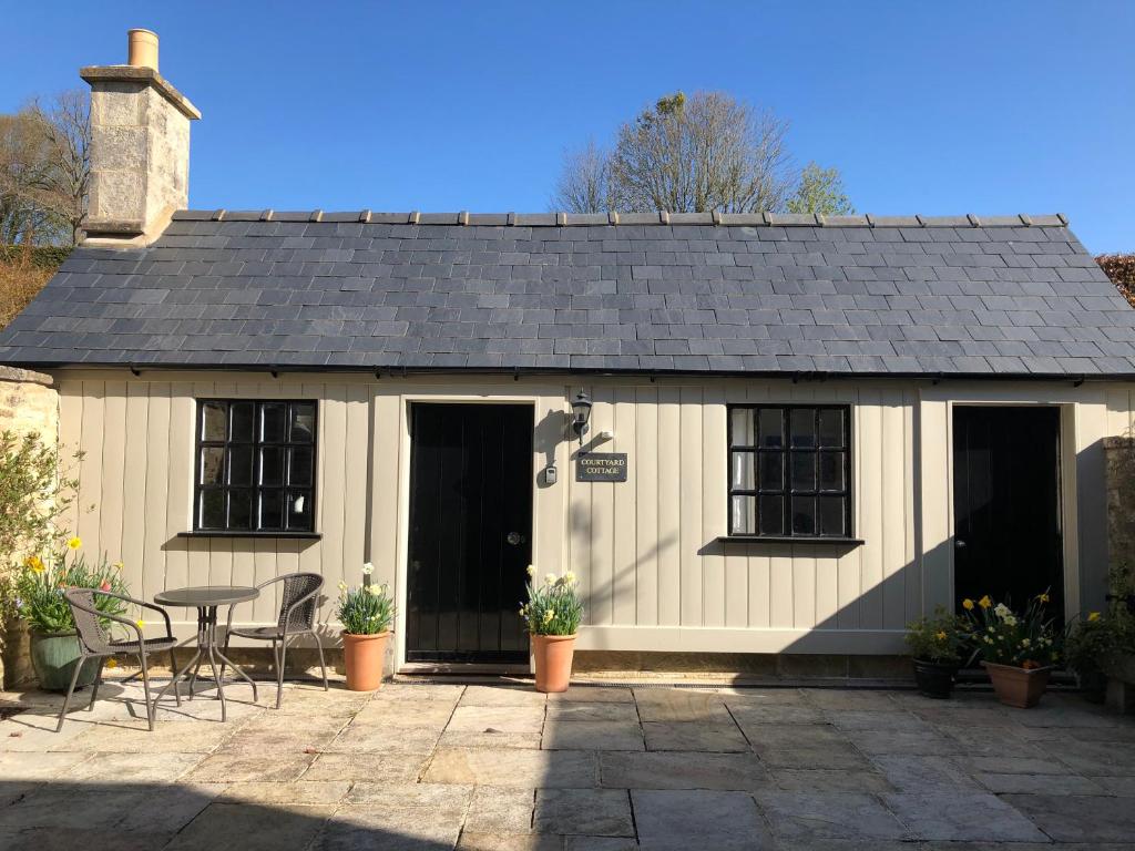 un cottage con tavolo e sedie di fronte di Courtyard Cottage a Stroud