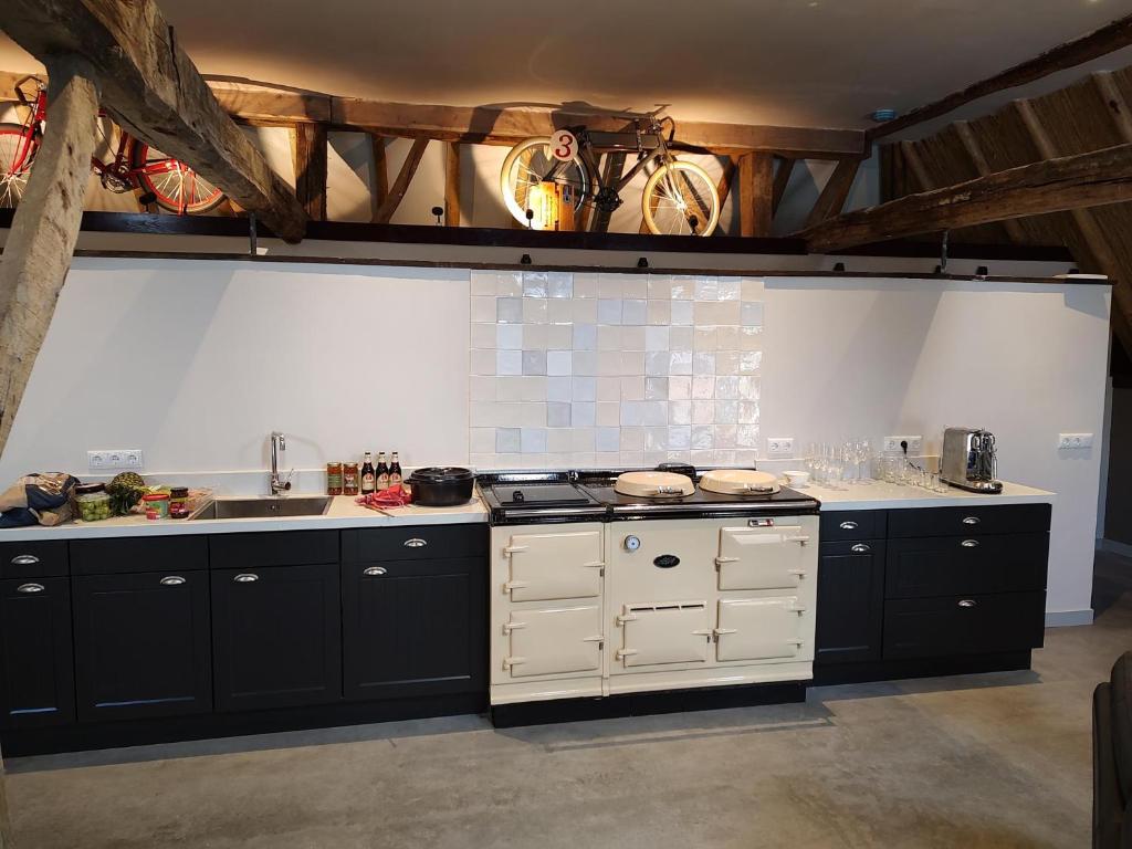 a kitchen with black and white cabinets and a stove at Juweeltje van vakantiewoning op prachtig landgoed in Nieuwleusen