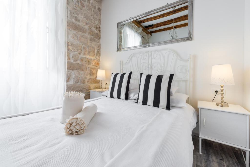 Dormitorio blanco con cama blanca y almohadas blancas y negras en Premium Apartment, en Dubrovnik