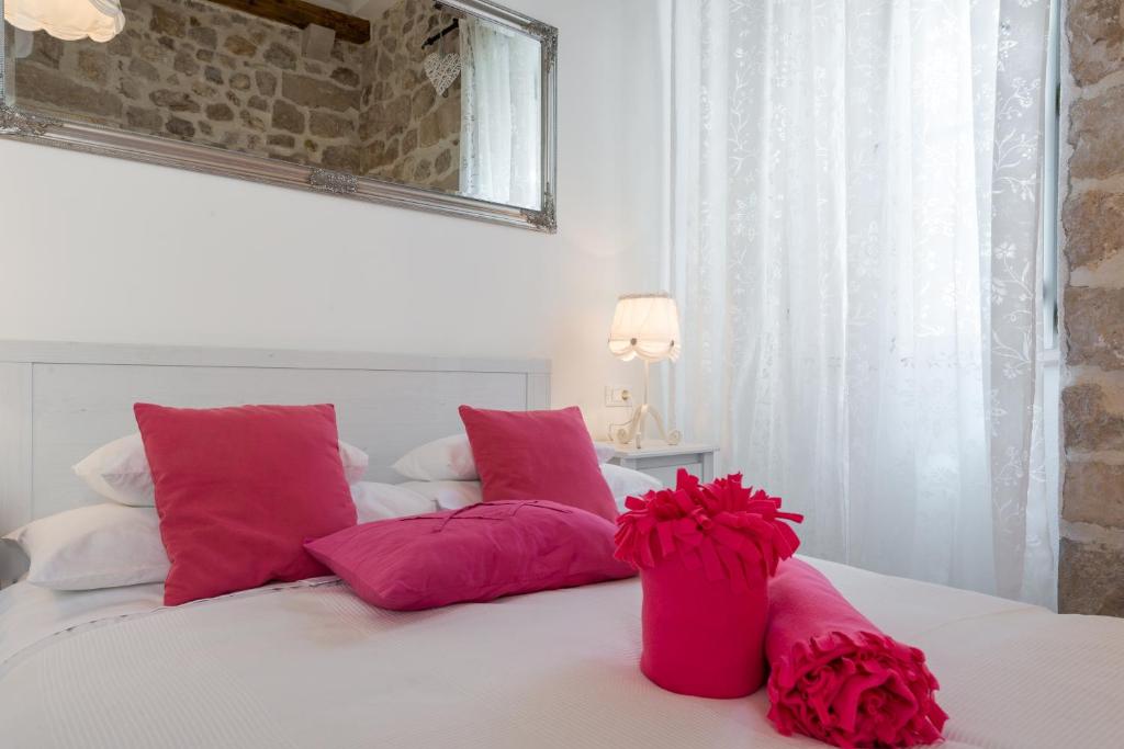 a bed with pink pillows and red flowers on it at Luxury Rose Apartment in Dubrovnik