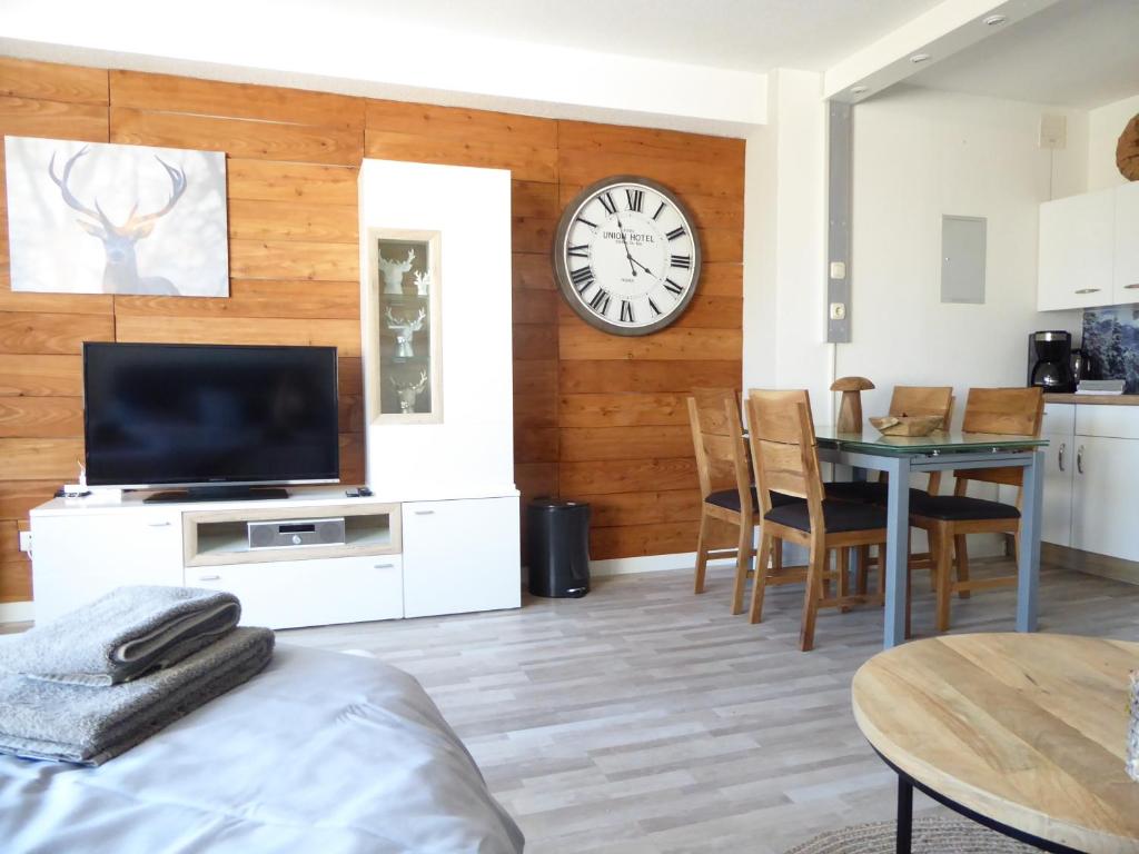 a living room with a table and a clock on a wall at Mountain Suite Winterberg Ferienwohnung Pool Sauna Hund 4 Pers Wifi near Ski Lift in Winterberg