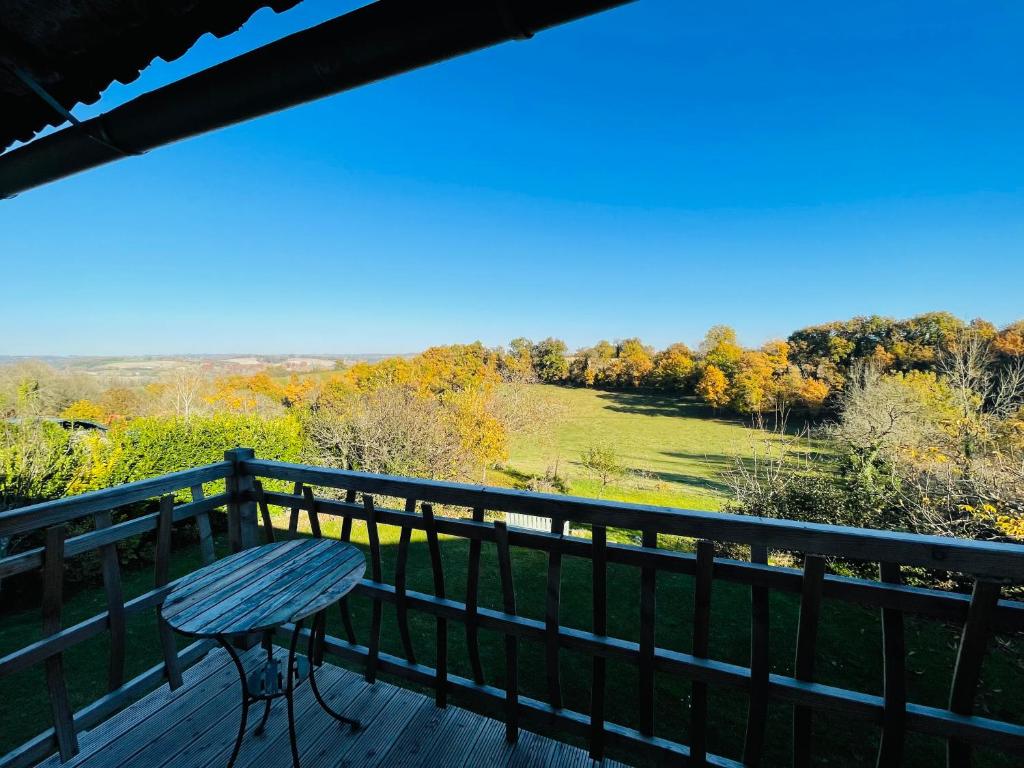 a table on a deck with a view of a field at gîte chêne doré in Ribérac