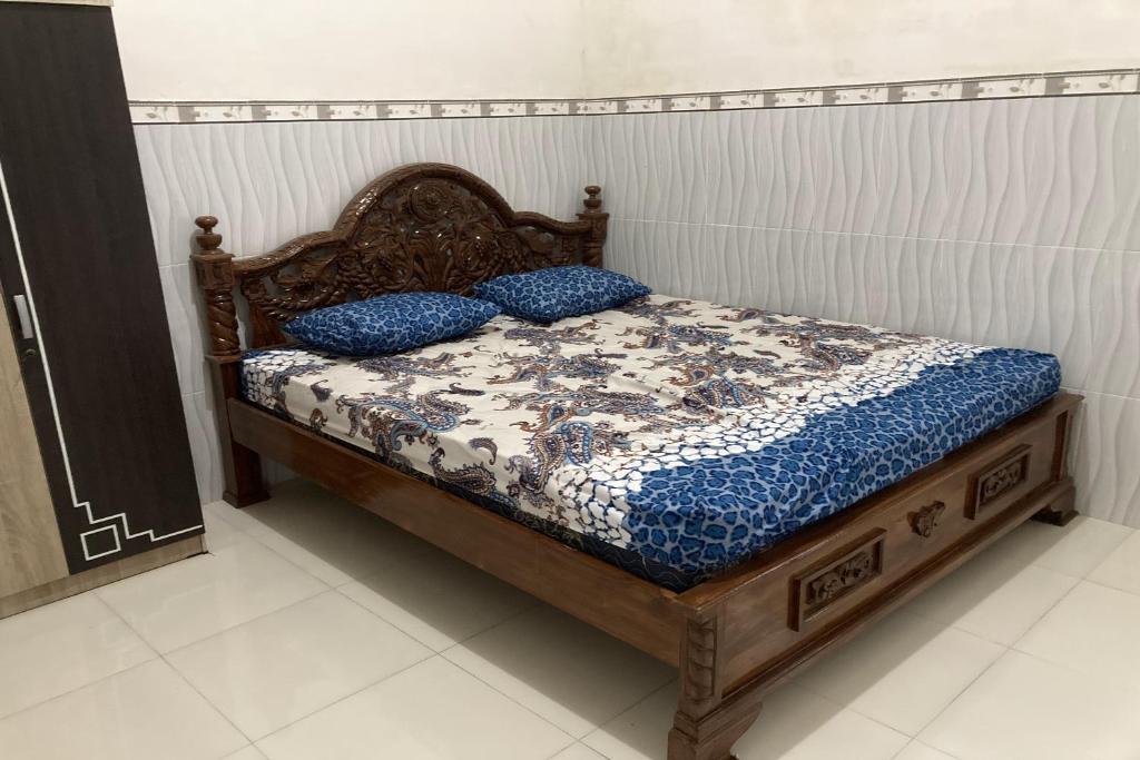 een bed met twee blauwe kussens in een kamer bij OYO Homes 91136 Desa Wisata Dalegan in Sukowati