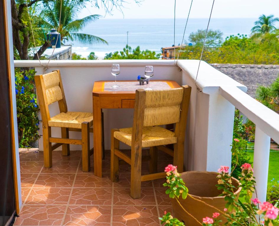 einen Tisch und Stühle auf einem Balkon mit Meerblick in der Unterkunft La Hacienda Tilantongo in Puerto Escondido