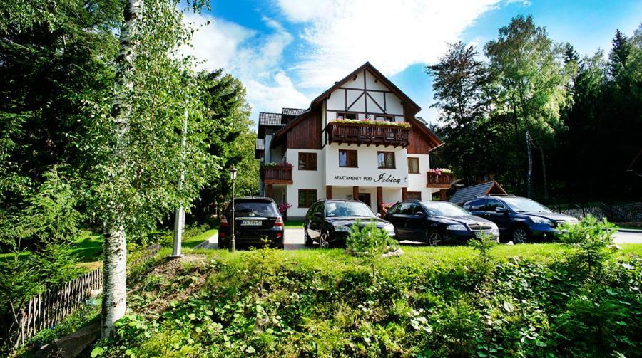a house with cars parked in front of it at Apartamenty Pod Izbicą in Karpacz
