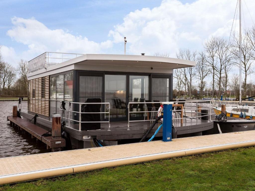 a small boat parked at a dock on the water at Houseboat with Stunning Views in Sneek