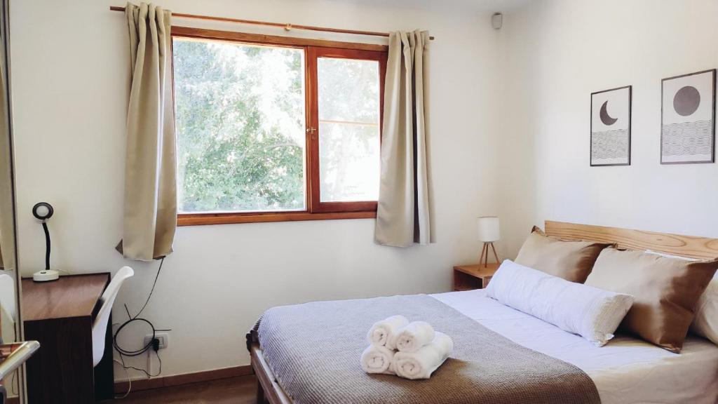 a bedroom with a bed with two towels on it at Casa con jardín y cochera ¡A 5 minutos del lago! in San Carlos de Bariloche