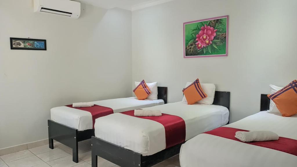 3 camas en una habitación con paredes blancas en Cahaya Adrian Near Komodo Airport en Labuan Bajo