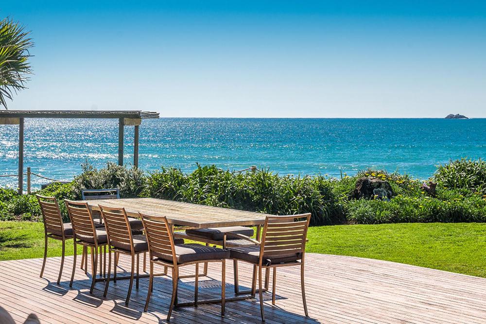 a wooden table and chairs with the ocean in the background at Fuller Holidays - Belongil Beachfront Pavilion, 18 Childe St in Byron Bay