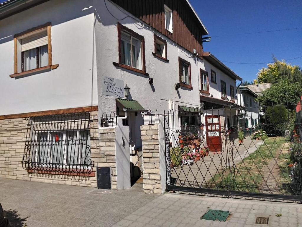 ein weißes Gebäude mit einem Tor davor in der Unterkunft Residencial Sissus in San Carlos de Bariloche