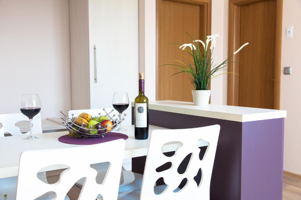 a table with a bowl of fruit and a bottle of wine at Sky Apartments in Blagoevgrad