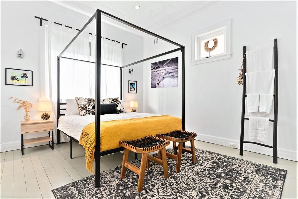 ein Schlafzimmer mit einem Himmelbett und einem Teppich in der Unterkunft Bondi Surf Cottage in Sydney