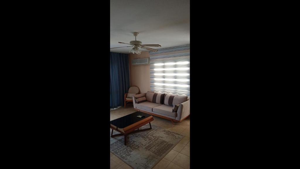 a living room with a couch and a ceiling fan at Room in Apartment - Kadinlar Denizi Ev 31 in Aydın
