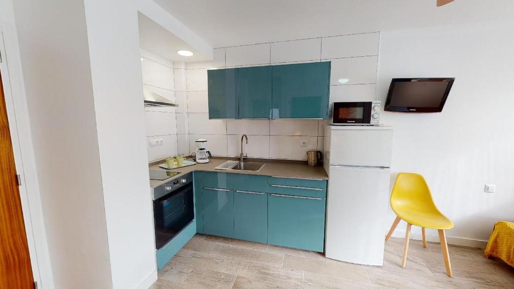 a kitchen with blue cabinets and a yellow chair at Apartamentos Eldorado in Lloret de Mar